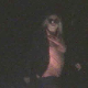 A heavy-set, blonde woman takes a very hard, nuggety dump on the road, lit only by car headlights.